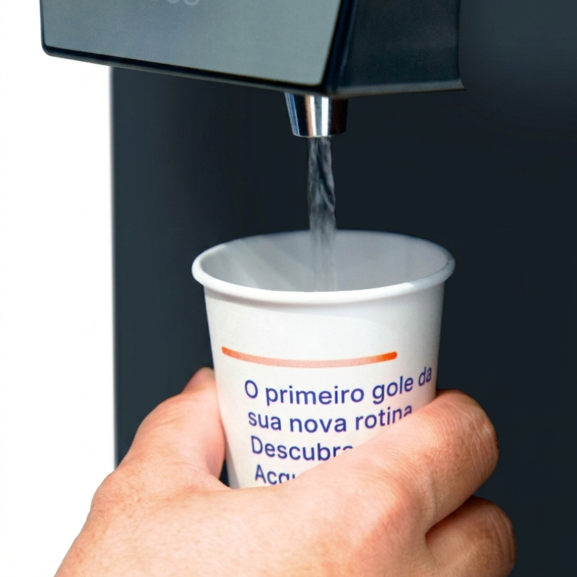 Mão enche copo de papel na saída de água do Acqualive DUO